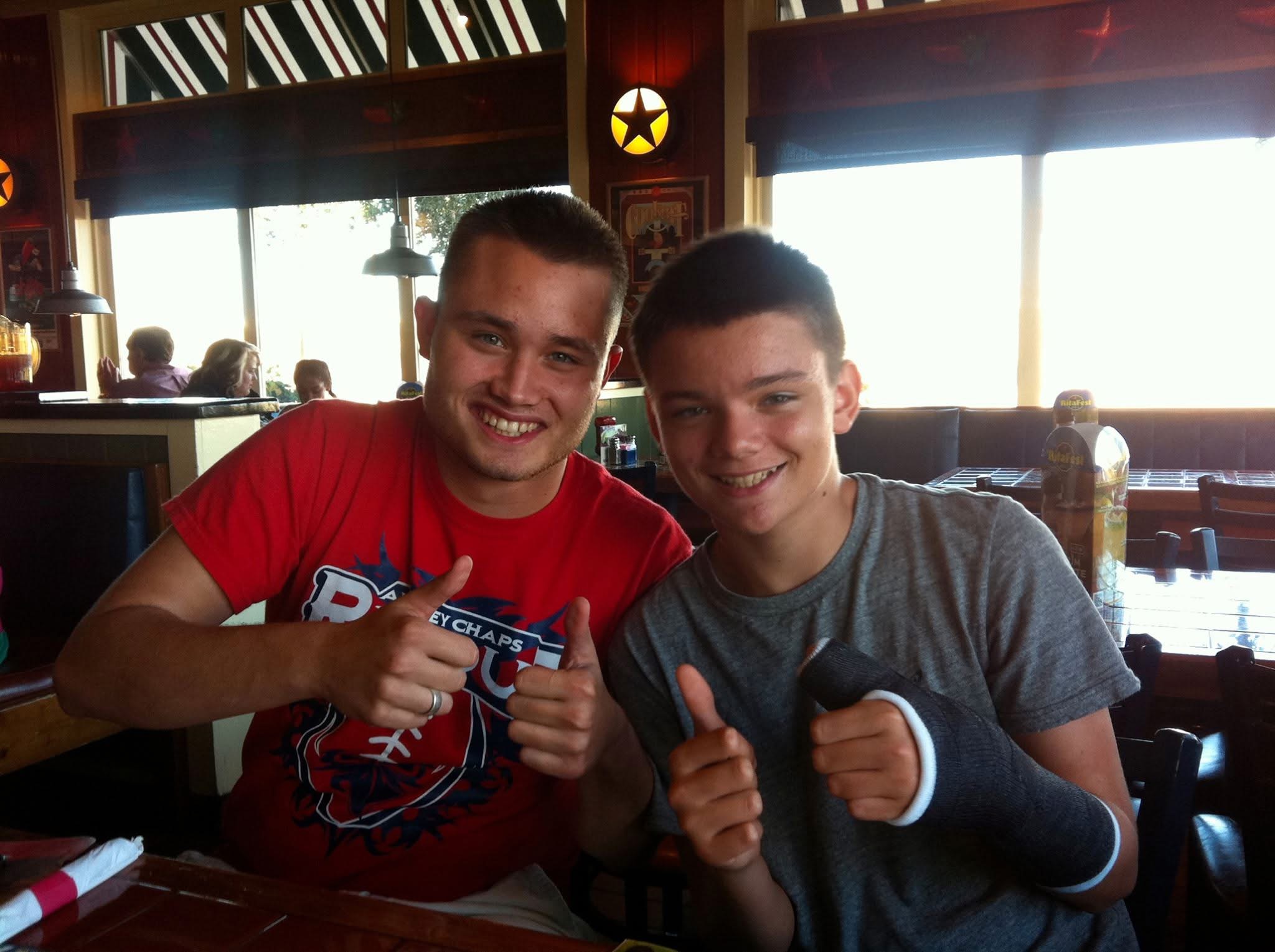Ryan and his younger brother giving thumbs up at a restaurant